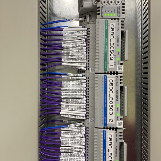 Purple cables with numbered markers running into a PLC input and output rack